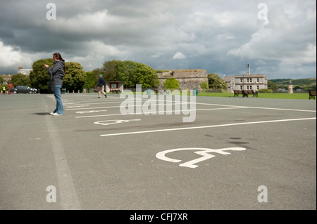 Ein Tourist steht in der Nähe eine leere Behindertenparkplatz gekennzeichnet durch eine Figur in einem Rollstuhl auf Plymouth Hacke. Stockfoto