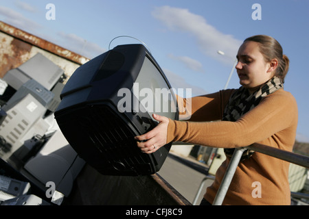 Frau wirft ein crt tv in überspringen auf Deponie Stockfoto