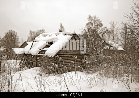 altes Holzhaus unter Winterschnee Stockfoto