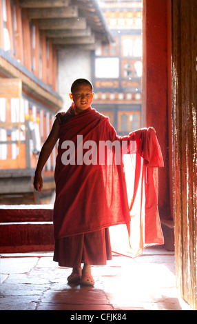 Young buddhistischer Mönch in roten Roben Hintergrundbeleuchtung durch Abend Sonnenlicht auf der Jakar Dzong, Jakar, Bumthang, Bhutan, Asia Stockfoto
