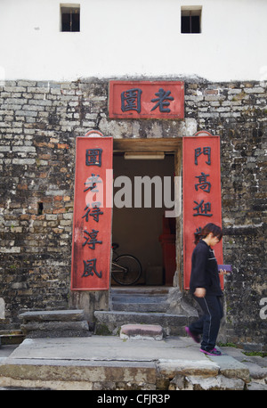 Frau zu Fuß aus der Tür des Lo Wai walled Village, Fanling, New Territories, Hong Kong, China, Asien Stockfoto