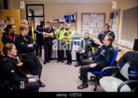 Eine Gruppe von uniformierten Polizeibeamten Sachwissen vor der Bereitstellung für den Einsatz an einem Samstagabend, UK Stockfoto