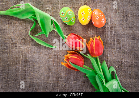 Oster-Deko mit bemalten Eiern und Tulpe Frühlingsblumen auf Leinwand Hintergrund Stockfoto