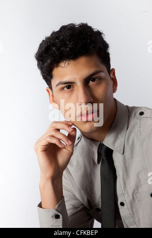 Hübscher Junge Hispanic Geschäftsmann mit Krawatte, Kinn in die Hand, mit einem ernsten und nachdenklichen Gesichtsausdruck in die Kamera schaut Stockfoto
