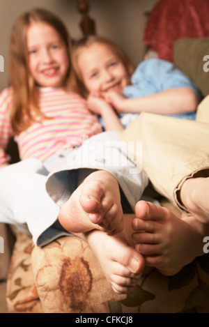 Zwei junge Mädchen barfuß Kichern auf Couch Stockfoto