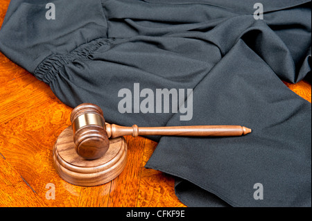 Ein Richter Kleid und Hammer mit soliden Block auf tiefen, satten farbigen hölzernen desktop Stockfoto