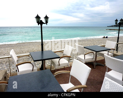 Terrasse hat der weiße Stühle, schwarzen Tischen und alt aussehenden Lampen nahe dem Strand und dem Mittelmeer Menton, südlich von Fr Stockfoto