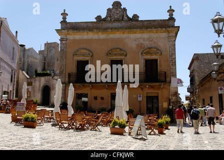 Erice. Sizilien. Italien. Blick auf die großen zentralen Piazza Umberto mit Café-Tischen und ehemaligen Palazzo jetzt als Bank genutzt. Die Stockfoto