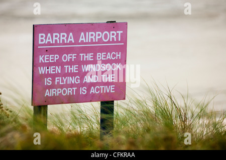 Ein Schild warnt vor Flugzeuge abheben von der Startbahn Strand auf der Insel Barra in die äußeren Hebriden Schottland im Rasen. Stockfoto