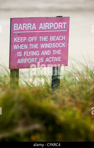 Ein Schild warnt vor Flugzeuge abheben von der Startbahn Strand auf der Insel Barra in die äußeren Hebriden Schottland im Rasen. Stockfoto