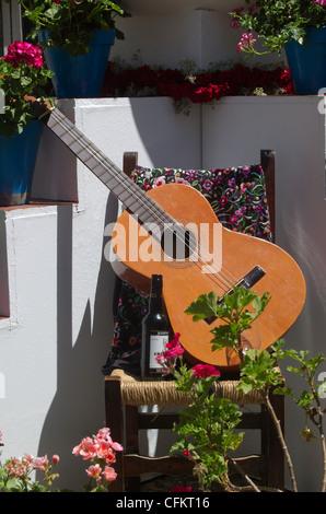 Gitarre auf Stuhl mit Flasche Wein als Opfergabe in die Cruces de Mayo Fiestas in Córdoba, Spanien. Stockfoto