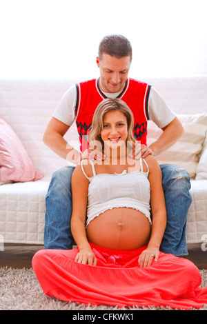 Junger Mann, der seine schwangere Frau massage