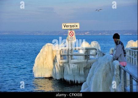 Die Anlegestelle in Versoix, Genfer See, bedeckt mit Eis. Die Figur im Bild ist keine Person, sondern ein Schaufenster Dummy. Stockfoto