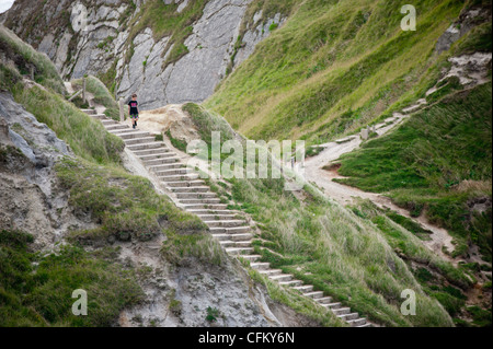 Ein Junge geht auf dem Küstenpfad zu Durdle Door in Dorset, Großbritannien Stockfoto