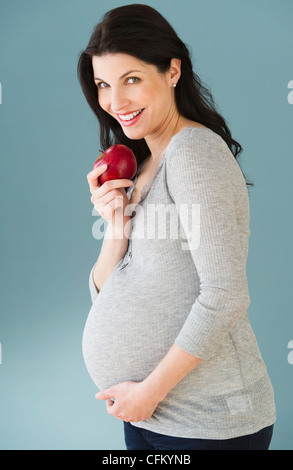 Studio-Porträt der schwangeren Frau Essen Apfel Stockfoto