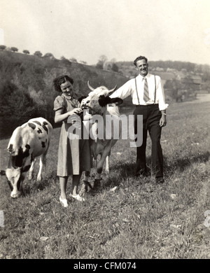 Gut gekleidete paar mit Kühe am Hang Stockfoto