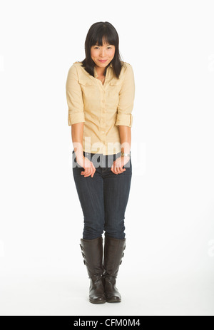 Mitte adult lächelnde Frau stehend, Studio gedreht Stockfoto