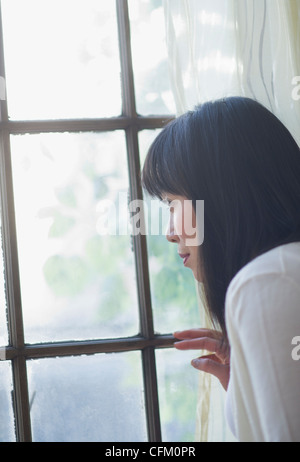 USA, New Jersey, Jersey City, nachdenkliche Frau Blick durch Fenster Stockfoto