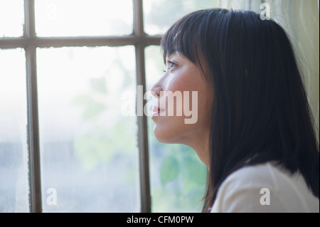 USA, New Jersey, Jersey City, nachdenkliche Frau Blick durch Fenster Stockfoto