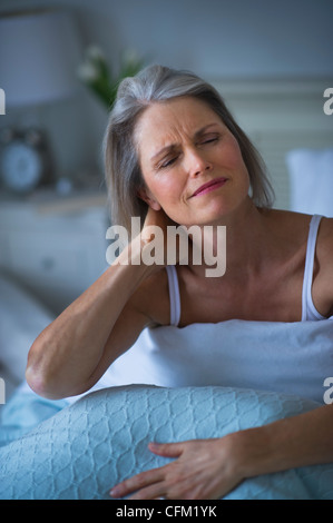 USA, New Jersey, Jersey City, Senior Frau im Bett sitzen und Leiden Halskette Stockfoto