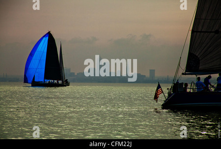 zwei Segelboote vor den nebligen Umriss von Cleveland, Ohio - Sonnenlicht durch blaue Spinaker und amerikanische Flagge Stockfoto