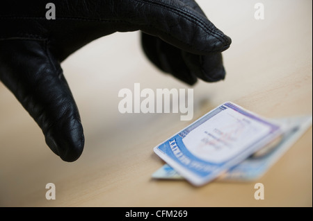 Nahaufnahme eines Diebes Hand in schwarzen Handschuh, Führerschein, Studio gedreht zu stehlen Stockfoto