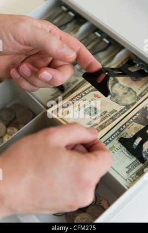 Nahaufnahme von Menschenhand, Banknoten in die Registrierkasse, Studioaufnahme Stockfoto