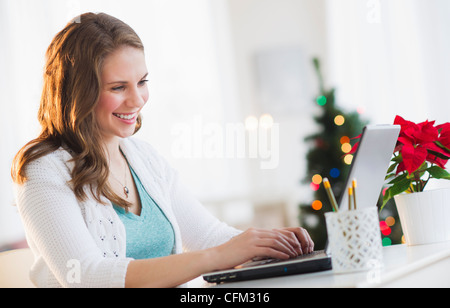 USA, New Jersey, Jersey City, junge Frau, die Arbeit am Laptop mit Weihnachtsbaum im Hintergrund Stockfoto