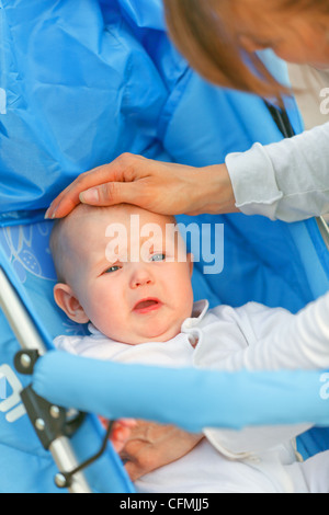 Fürsorgliche Mutter, die beruhigende, sitzend im Kinderwagen schreiendes Babymädchen Stockfoto