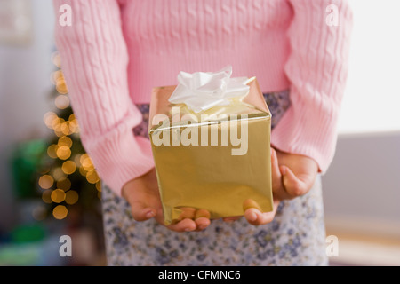 USA, California, Los Angeles, Close-up of girl holding Christmas present behind back, mid section Stockfoto