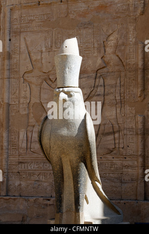 Edfu. Ägypten. Afrika. Blick auf die einzelnen Granitstatue des Horus, die vor der Säulenhalle am TheTemple des Horus sitzt. Stockfoto