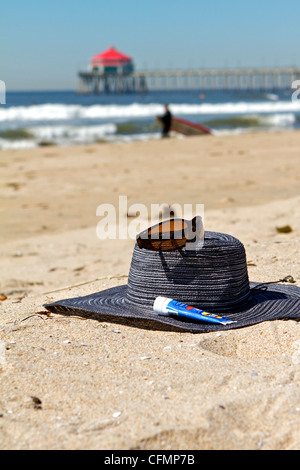 Women's Hut Sonnenbrille und Sonnencreme auf dem Sand in Huntington Beach Pier Kalifornien Stockfoto