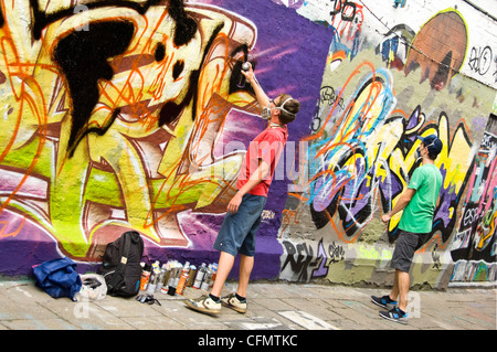 Horizontale Ansicht der Graffiti Gasse Werregaran Straat in Gent, mit zwei Künstlern Spritzlackierung ihre Kunst auf dem Gehweg-Wand. Stockfoto