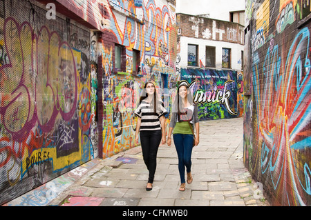 Horizontale Ansicht von Graffiti Gasse Werregaran Straat in Gent, mit zwei jungen Mädchen die Graffiti-Kunstwerke an den Wänden betrachten Stockfoto