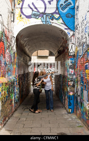 Vertikale Ansicht von Touristen auf der Suche auf Graffiti-Kunstwerk auf jeder Fläche Graffiti Gasse, Werregaran Straat in Gent. Stockfoto