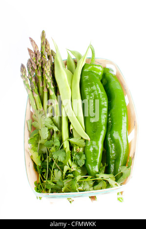 Korb mit frisch gepflückten Bohnen, Spargel, Paprika und Petersilie kochbereit, isoliert auf weiss. Stockfoto