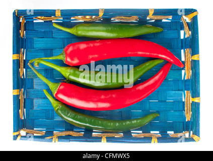 Rot und grün hot Chili Peppers in einem blauen indischen Korb isoliert auf weiss. Stockfoto