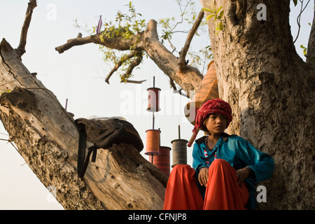 Eine junge Entertainer auf Stelzen sitzt auf den Ästen eines Baumes während einer Drachenfliegen Festival am India Gate Stockfoto