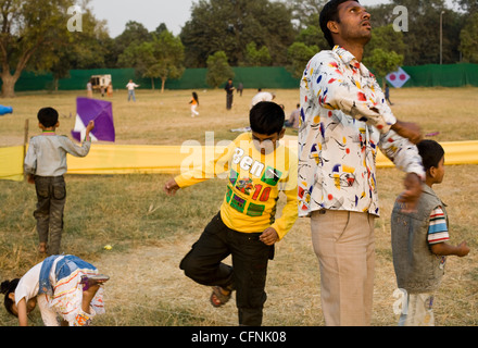 Kinder versuchen, über einen Mann Drachenschnur steigen, wie er einen Drachen fliegt während einer Drachenfliegen Festival am India Gate, Neu-Delhi Stockfoto