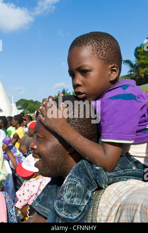 Vater mit seinem Sohn auf seinen Schultern beim Betrachten einer Regatta der Angelboote/Fischerboote in Stone Town Sansibar Tansania Stockfoto