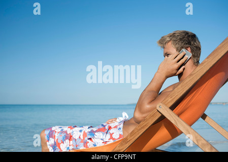 Junger Mann reden über Handy am Strand Stockfoto