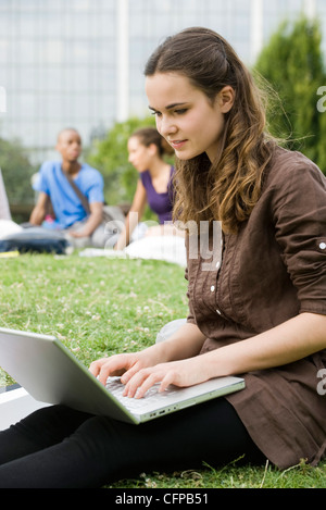 Junge Frau mit Laptop-Computer im Freien, Menschen im Hintergrund, Porträt Stockfoto