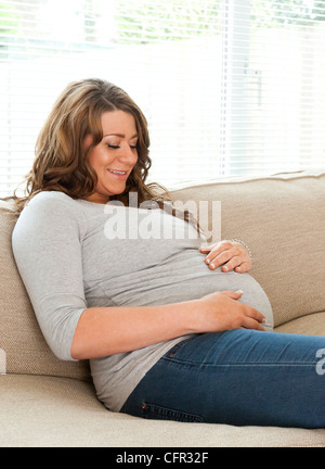 Schwangere Frau saß auf dem sofa Stockfoto