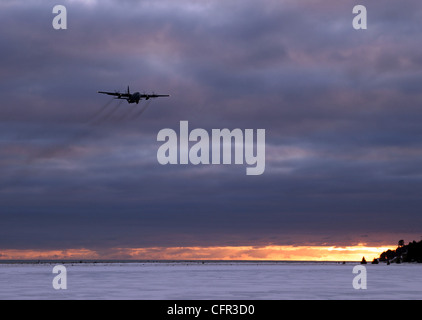 Luftwaffe Flugzeug kommen, um an einem stürmischen Winterabend in Homer Alaska bei Sonnenuntergang mit dunklen Wolken zu landen. Stockfoto