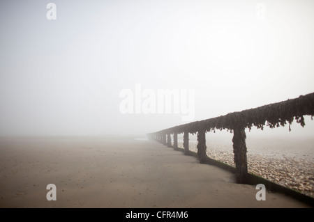 Nebel Wolken Sandown Beach auf der Isle Of Wight. Hölzerne Buhnen verschwinden in der niedrigen Wolken im englischen Badeort. Stockfoto