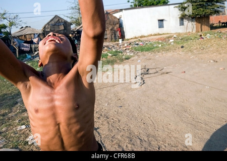 Ein junger Mann, der eine Schnitzeljagd ist, genießt eine Partie Volleyball bei der Stung Meanchey Mülldeponie in Phnom Penh, Kambodscha. Stockfoto