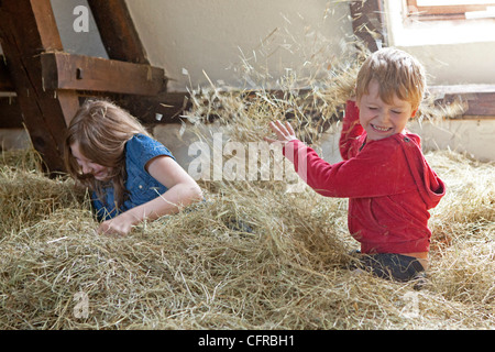 zwei Kinder spielen im Heuhaufen Stockfoto