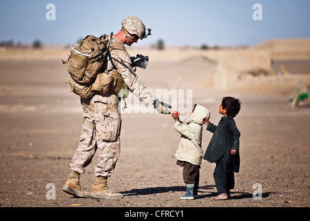 U.S. Marine Lance Cpl. Tom Morton Hände einem afghanischen Kind eine Spielzeug während einer Sicherheitspatrouille 25. Februar 2012 in Safar Basar, Afghanistan. Stockfoto