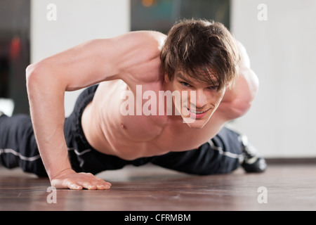 Muskulöser Mann auf diese Weise Liegestütze mit nur einem Arm in einem Fitnessstudio trainieren Stockfoto