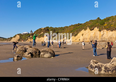 Touristen posieren und Fotografieren bei Moeraki Boulders bei Ebbe, Otago, Neuseeland. Stockfoto